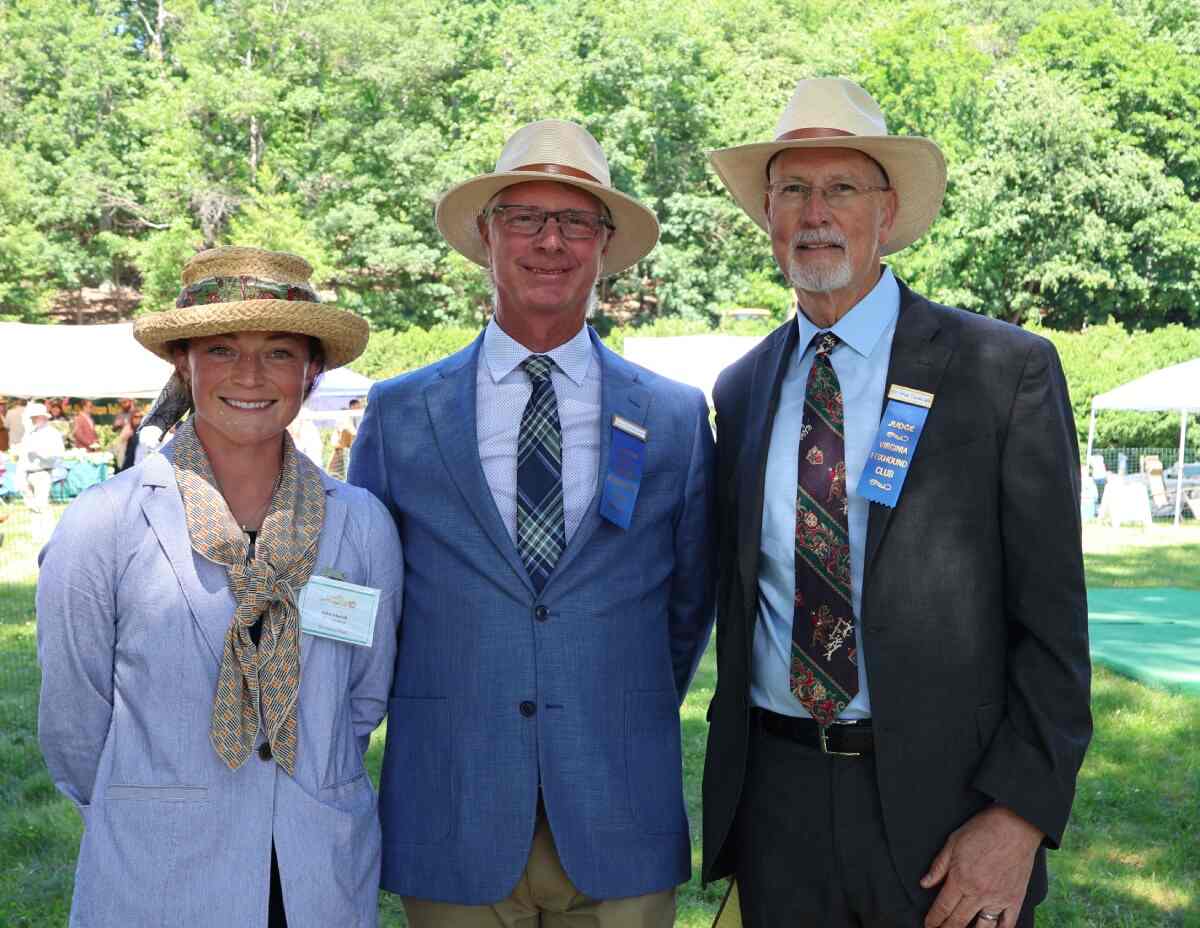 Woman and two men in suits, all wearing straw hats