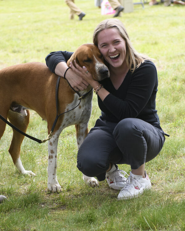 smiling woman hugging red and white foxhound